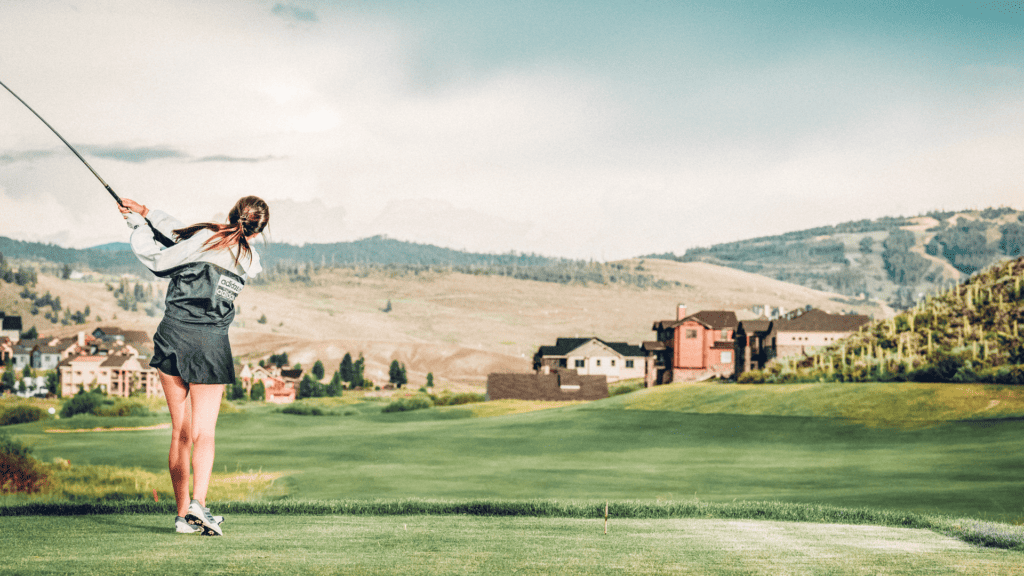 A woman swinging a golf club on a golf course.