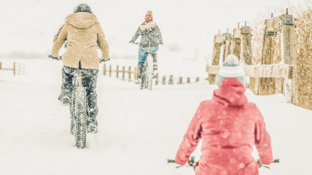 A group of people riding bikes in the snow.