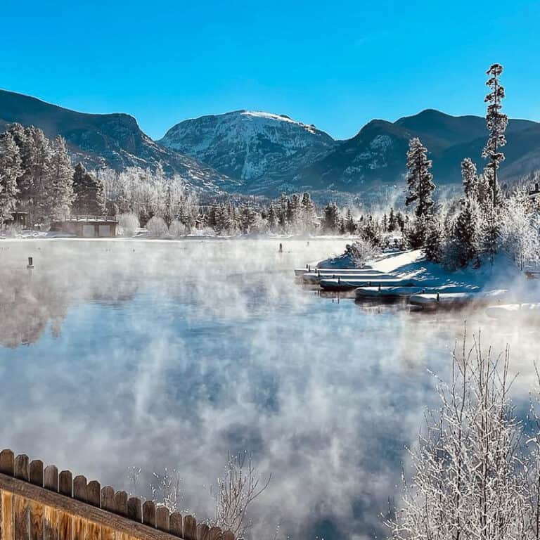 A winter scene with a lake and mountains in the background.