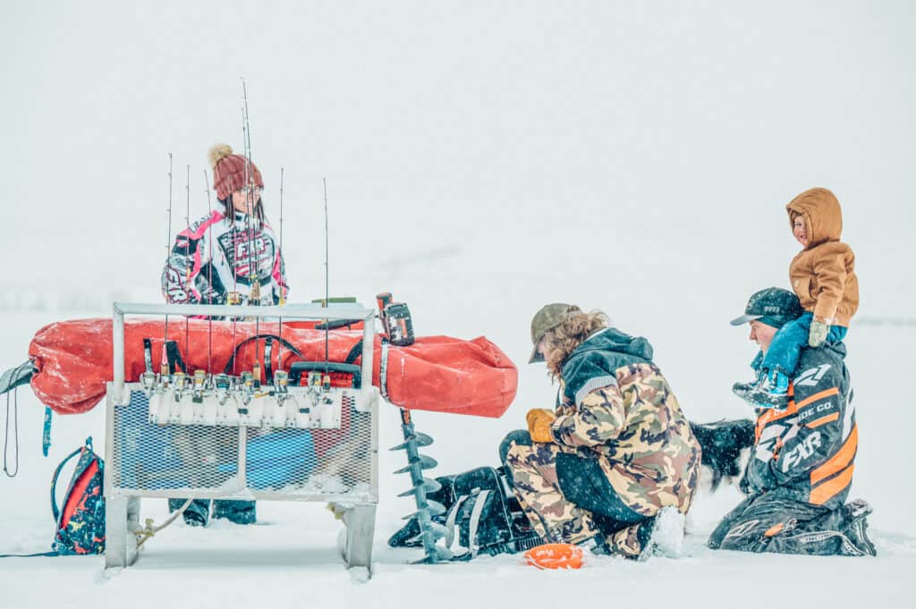 A group of people standing in the snow with a fishing rod.