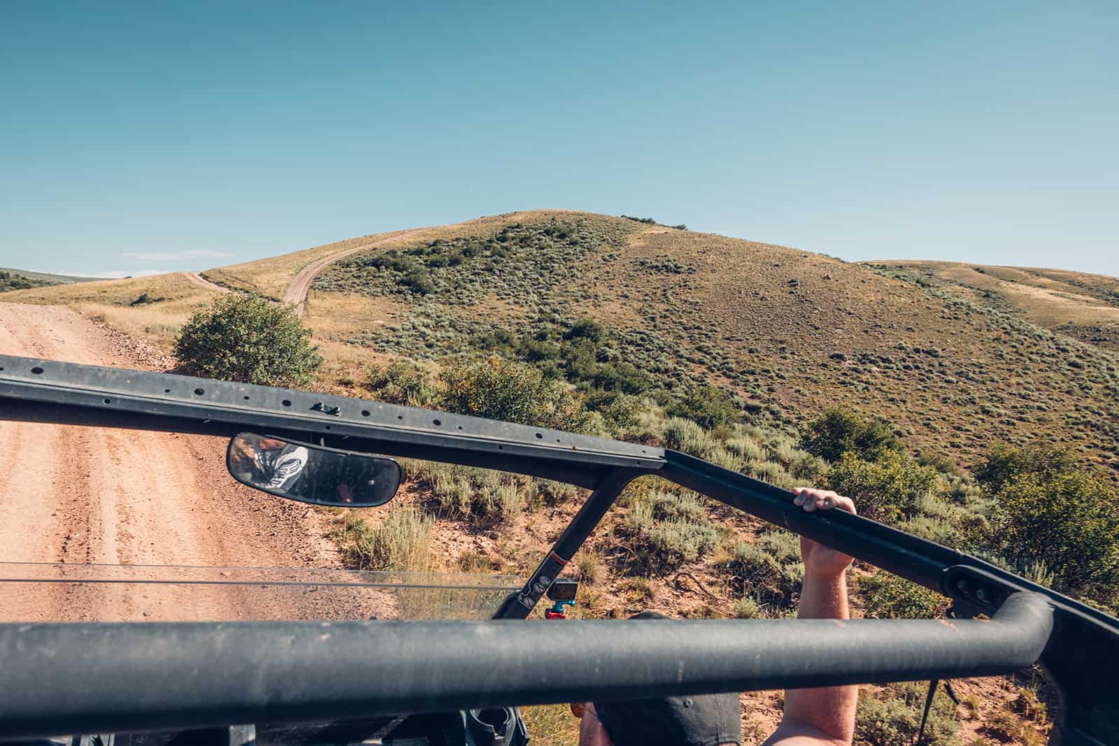 A man is driving a jeep down a dirt road.