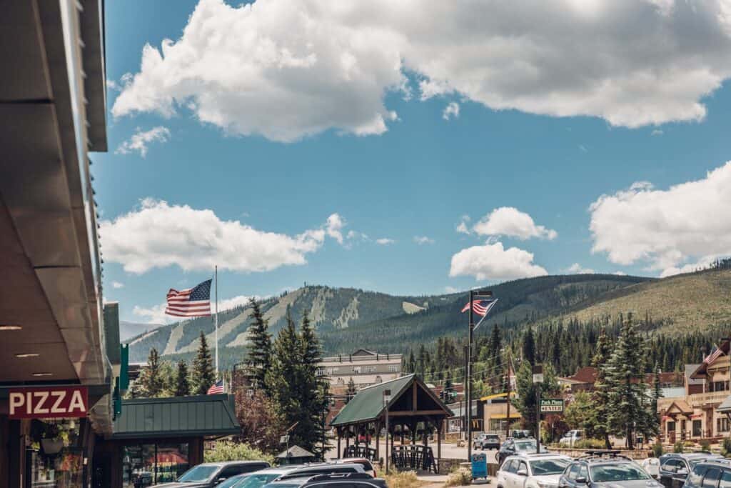 A street scene with cars parked in front of a mountain.