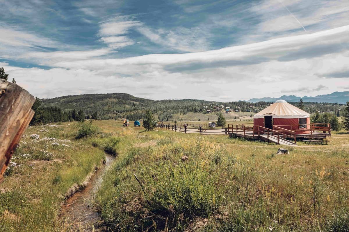 A yurt in the middle of a grassy field at YMCA of the Rockies in Granby