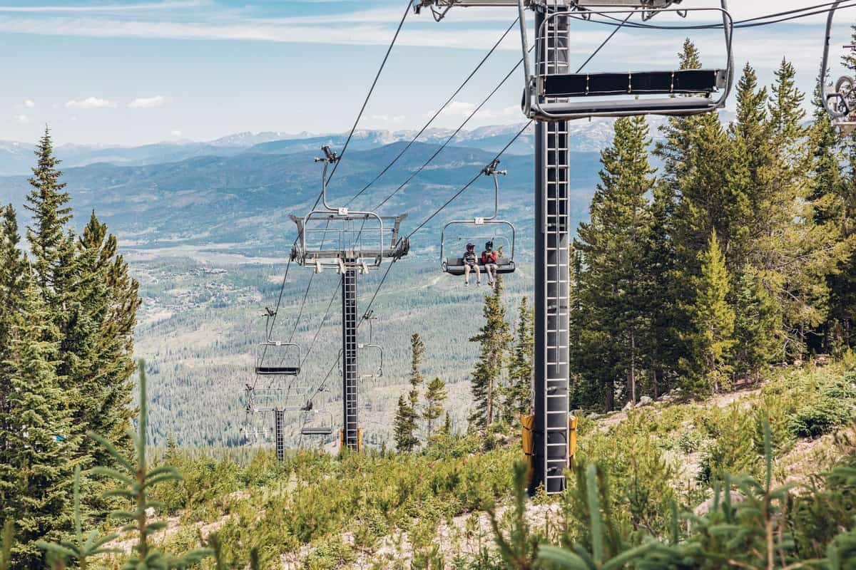 People ride on the summer gondola at Winter Park resort with the Continental Divide in the background.