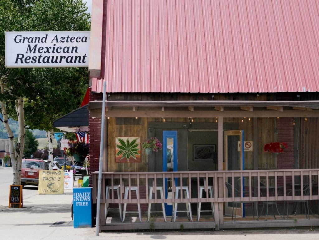 A vibrant pink-roofed restaurant with a wooden deck and a sign reading 'Grand Azteca Mexican Restaurant' in Grand County Colorado.