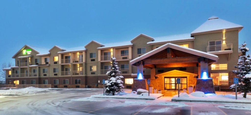A snow-covered hotel with a lit entrance and balconies, surrounded by evergreen trees in Grand County Colorado.