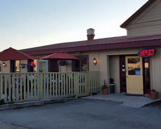 A quaint restaurant with outdoor seating, red umbrellas, and a yellow 'OPEN' sign in Grand County Colorado.