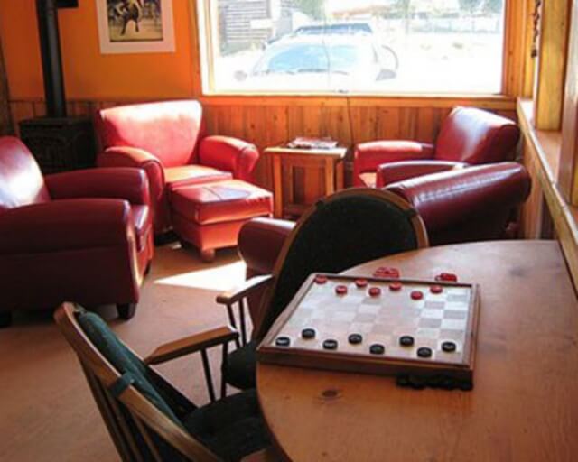 A cozy living room with red leather furniture, a wooden table, and a window overlooking a snowy landscape in Grand County Colorado.
