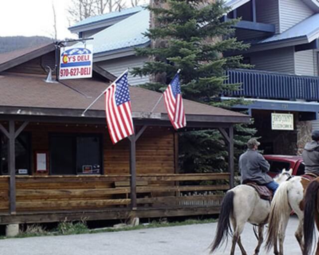 A rustic deli with American flags and a man on horseback outside in Grand County Colorado.