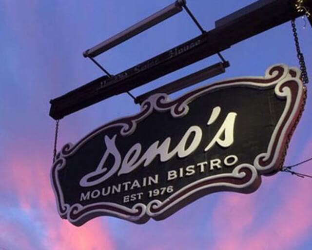 A vintage-style sign for Deno's Mountain Bistro, established in 1978, hangs against a colorful sky in Grand County Colorado.