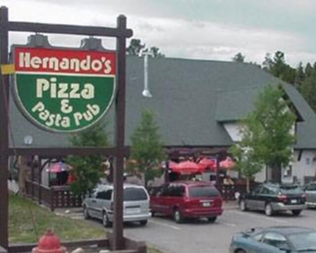 Sign for Hernando's Pizza & Pasta Pub with outdoor seating and parked cars in Grand County Colorado.