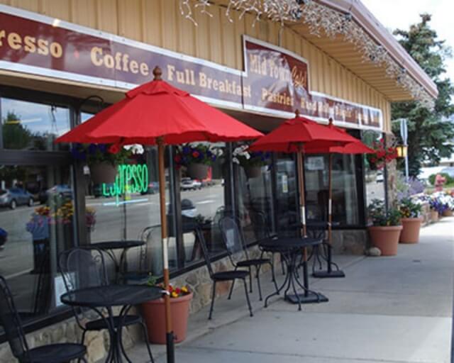 Outdoor seating area with red umbrellas and tables at a coffee shop in Grand County Colorado.