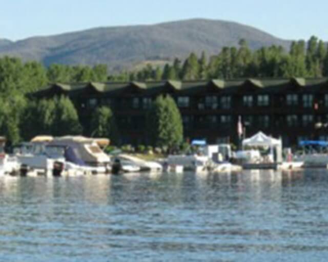 A serene marina with boats docked along a calm lake, surrounded by trees and mountains in Grand County Colorado.