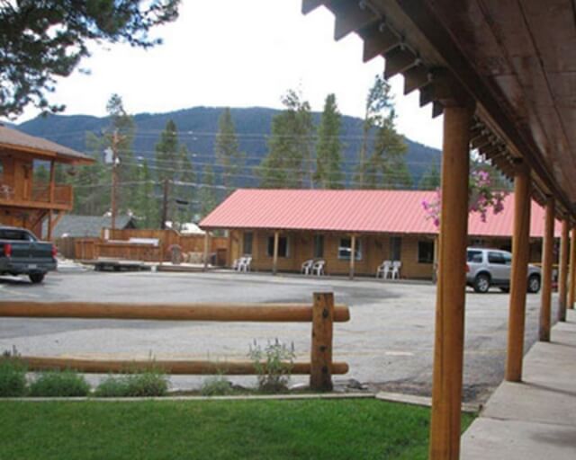 A rustic motel with red-roofed cabins and a wooden porch, nestled among trees in Grand County Colorado.