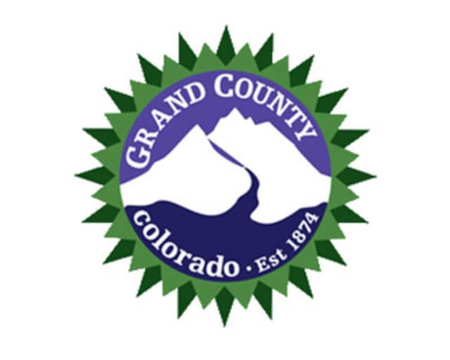 A circular emblem featuring a stylized mountain range and river, with 'Grand County Colorado' text in Grand County Colorado.