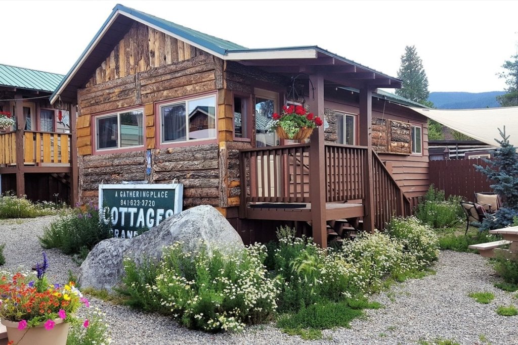 Rustic log cabin with flower garden and wooden deck in a natural setting in Grand County Colorado.