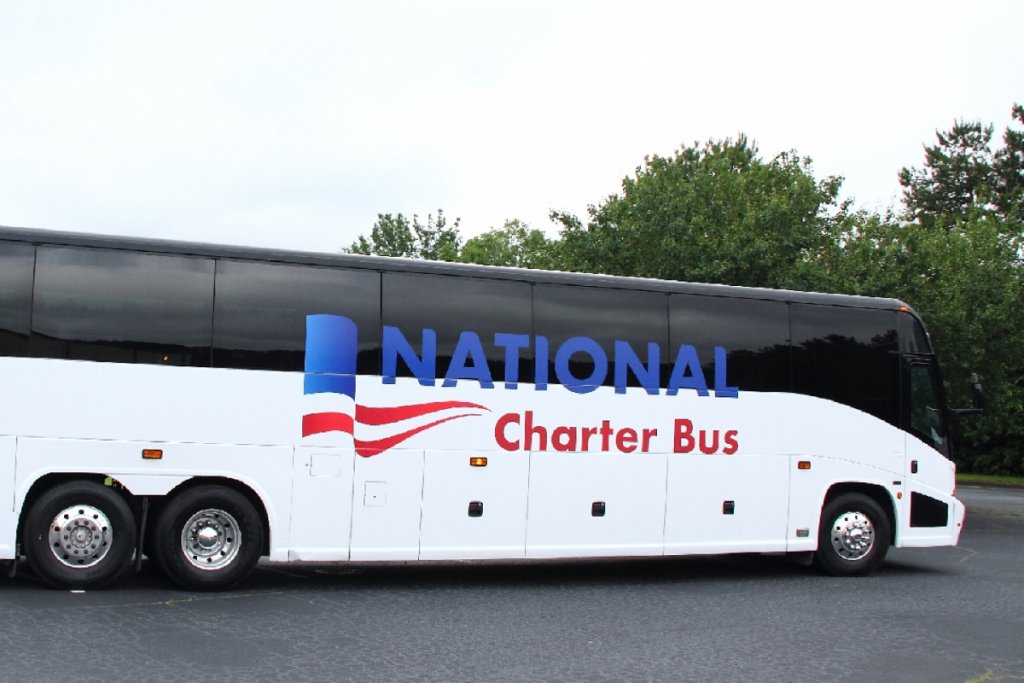 A large white charter bus with blue and red stripes and the words 'National Charter Bus' on the side in Grand County Colorado.