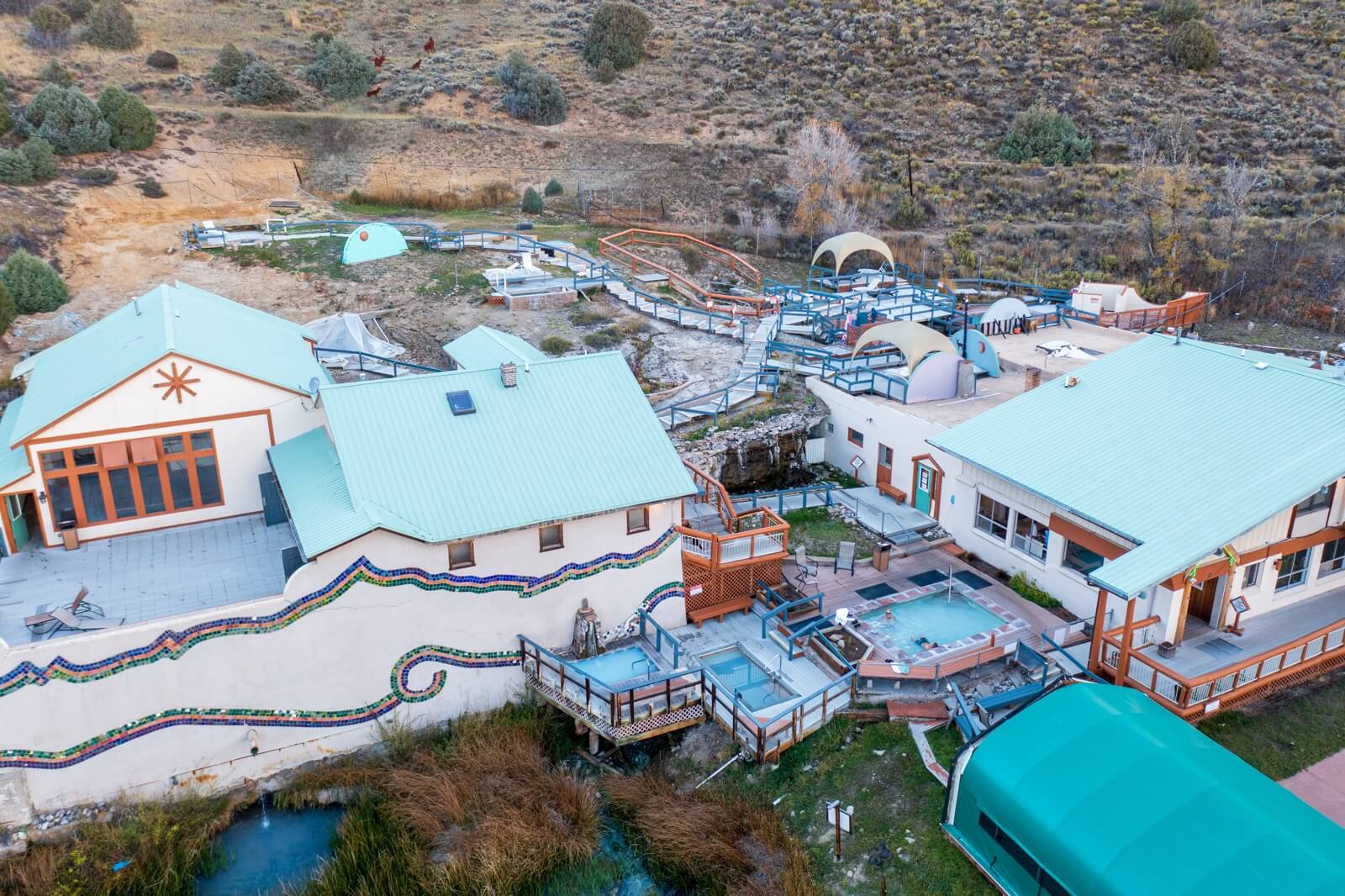 Aerial view of a multi-building complex with pools, hot tubs, and a winding water feature in Grand County Colorado.