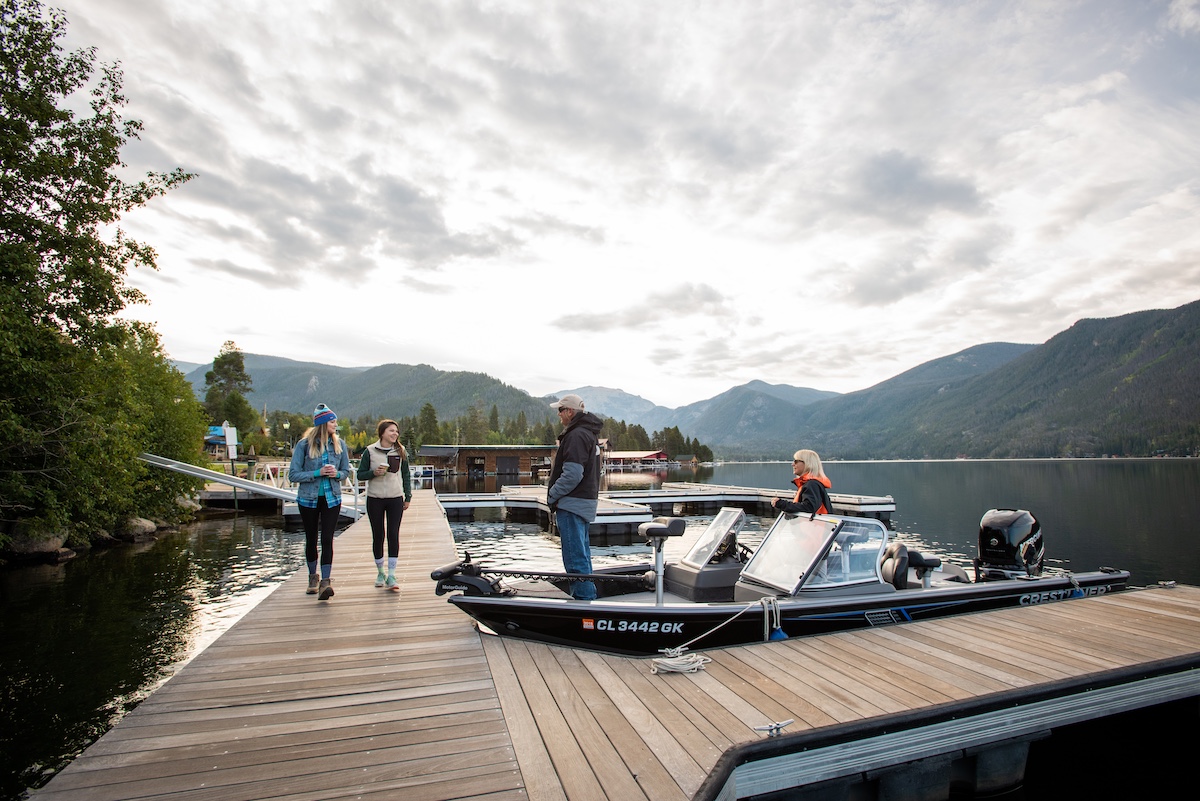 People walking on a wooden dock with boats and mountains in the background in Grand County Colorado.