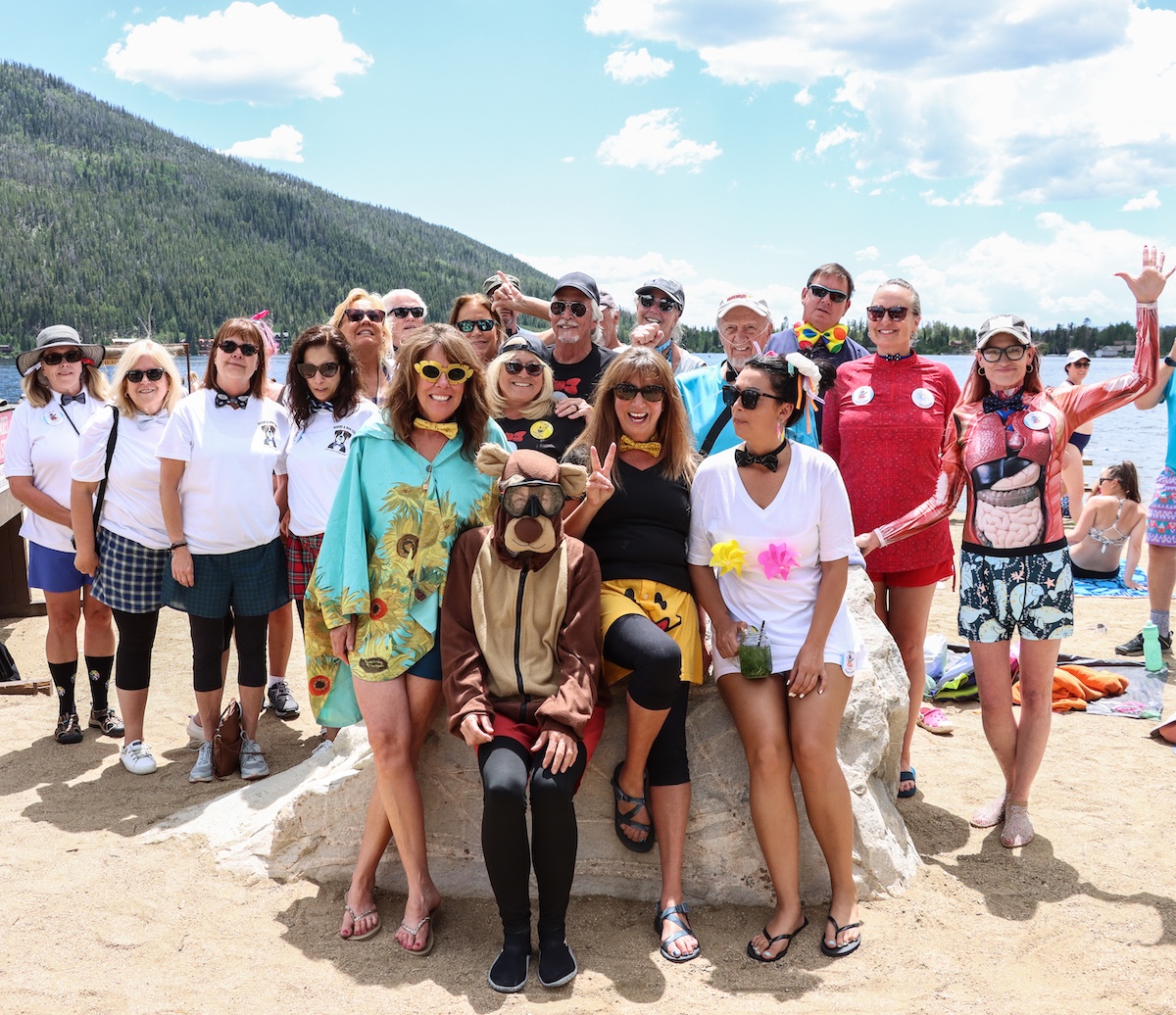 A group of people in colorful outfits and costumes pose together on a beach in Grand County Colorado.