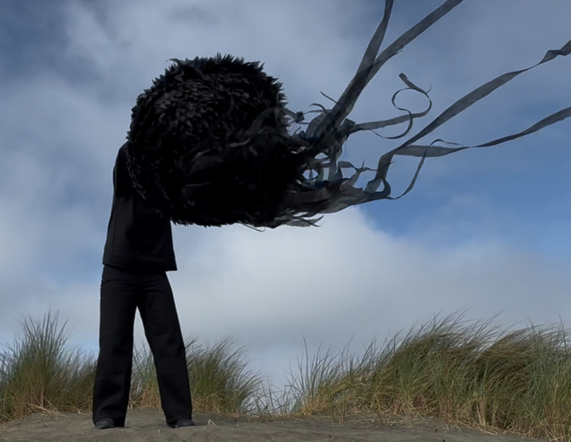 A person stands on a beach, holding a large, dark, tentacle-like object above their head in Grand County Colorado.
