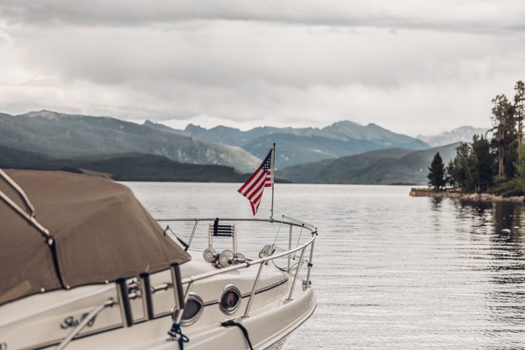 Boat with an American flag on Granby Lake with mountain views in the distance.
