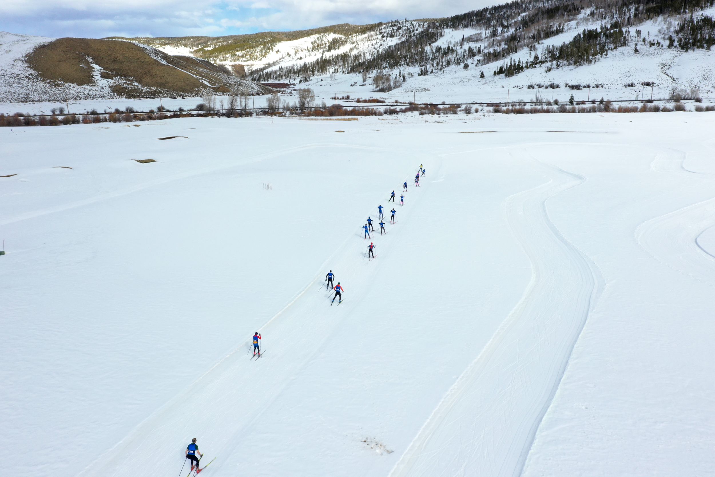 A group of cross-country skiers follows a winding trail through a snowy landscape in Grand County Colorado.