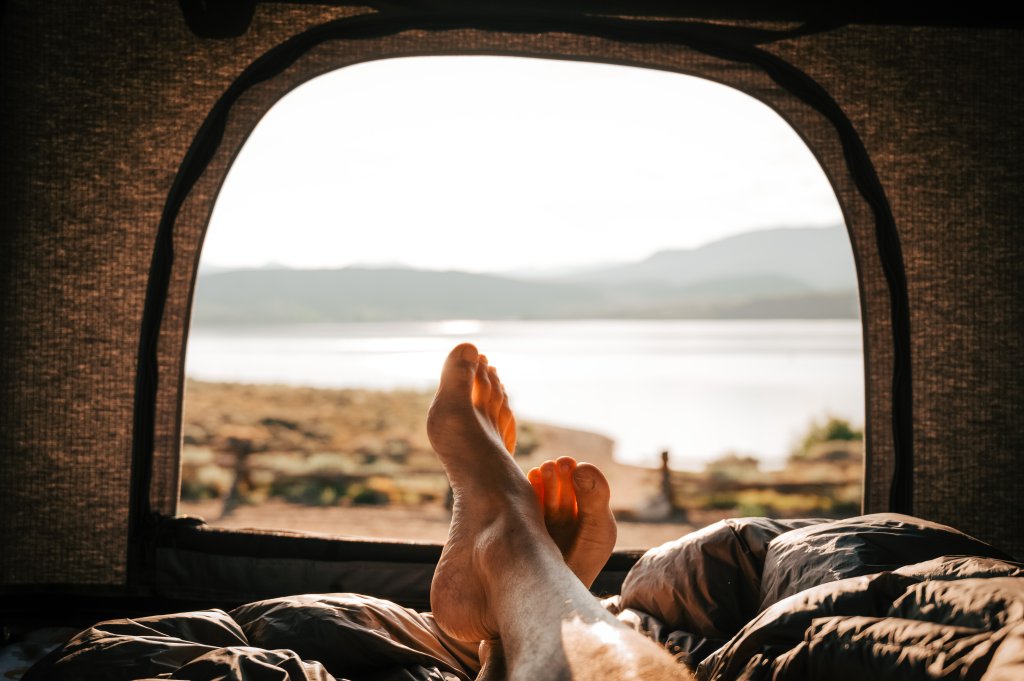 Bare feet relax in a tent with a scenic lake and mountain view outside in Grand County Colorado.