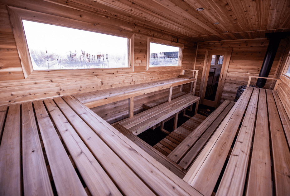 A cozy wooden sauna with benches and windows overlooking a snowy landscape in Grand County Colorado.