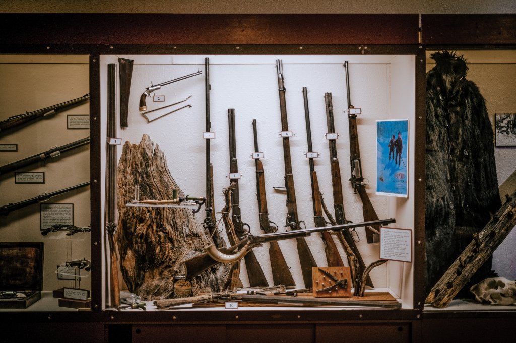 A museum display case filled with various antique firearms and related artifacts in Grand County Colorado.