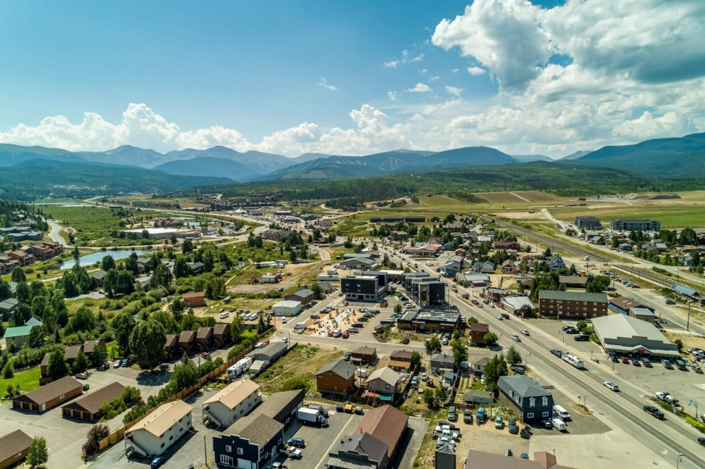 A picturesque town nestled in a valley with mountains in the background, featuring a mix of residential and commercial buildings, roads, and green spaces in Grand County Colorado.