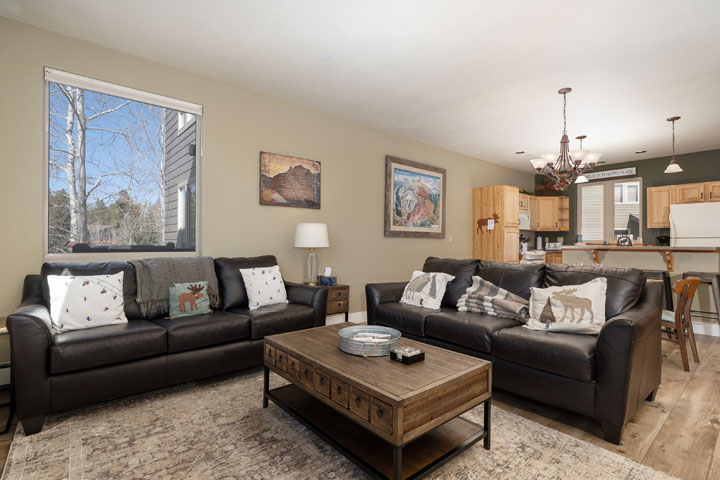 A cozy living room with black leather sofas, a wooden coffee table, and rustic decor in Grand County Colorado.