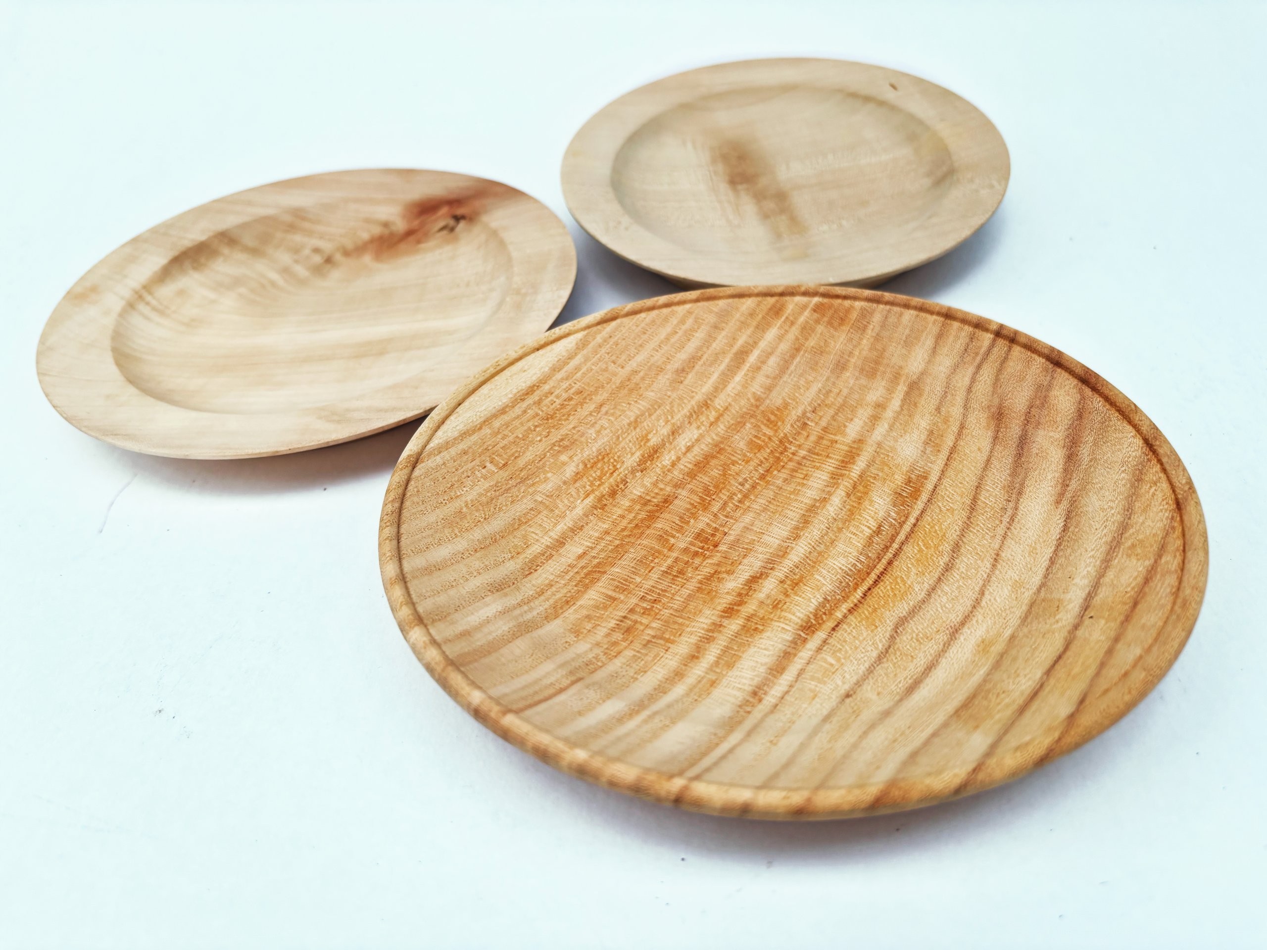 Three handcrafted wooden plates with varying sizes and natural grain patterns, showcasing the beauty of wood in Grand County Colorado.