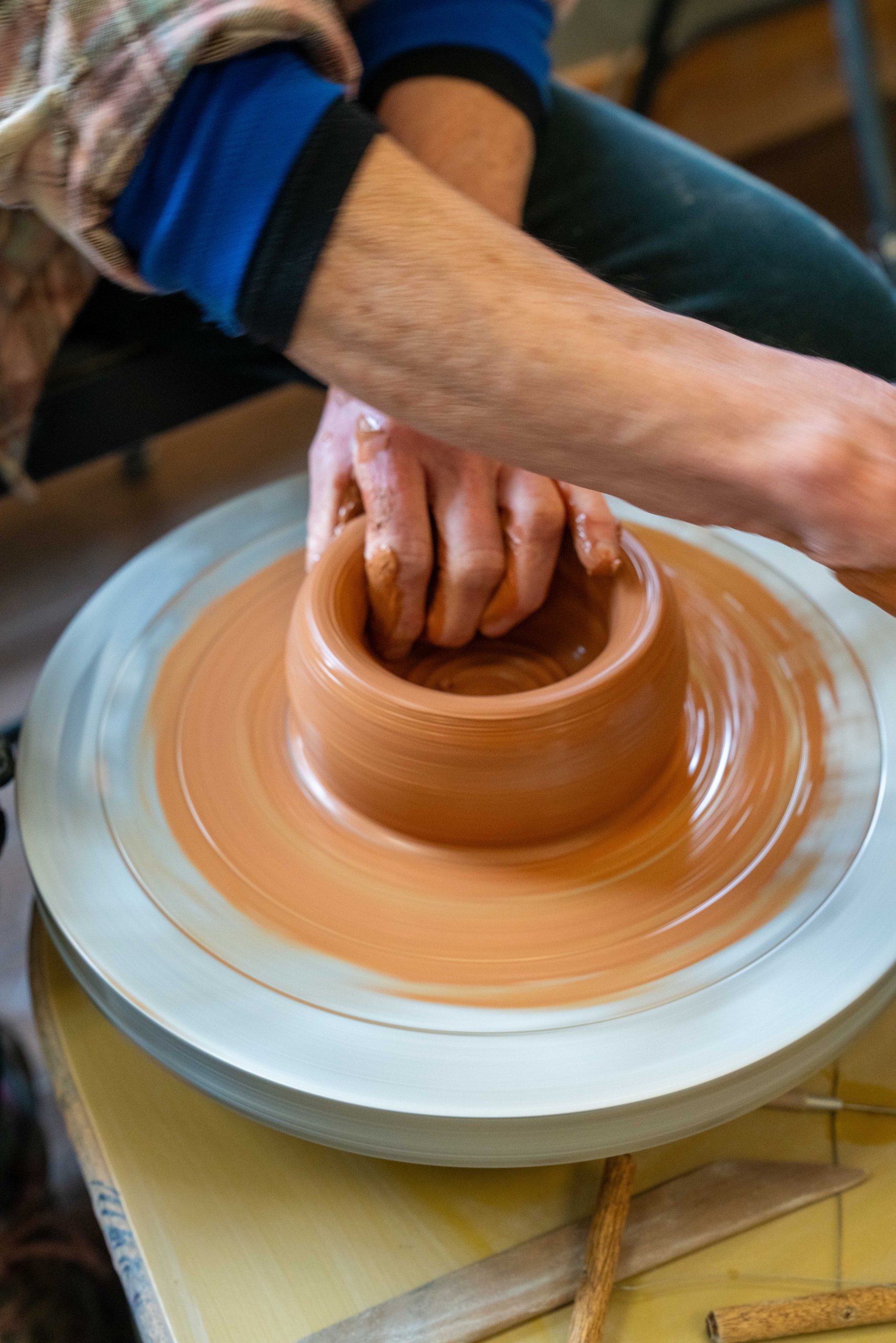 A skilled potter shaping a clay pot on a spinning wheel in Grand County Colorado.