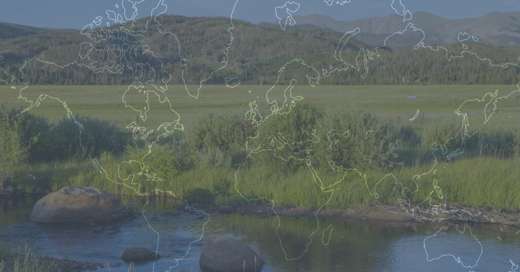 A serene landscape with a world map overlay, featuring a river, rocks, and lush greenery in Grand County Colorado.