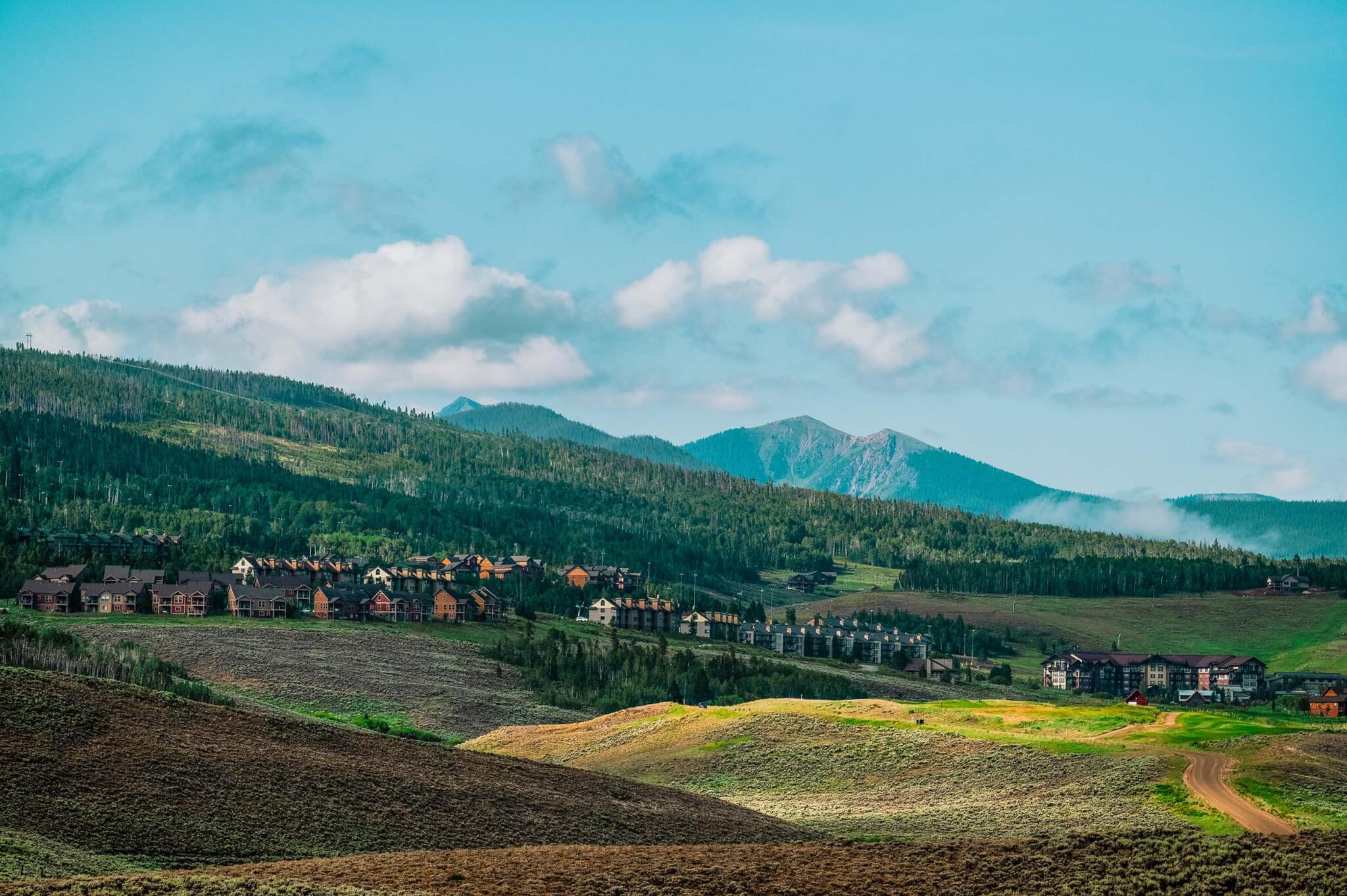 A view of the rolling hills and tree-covered mountains surrounding groups of buildings at Granby Ranch.