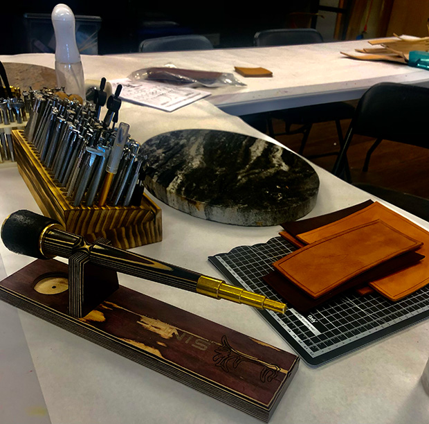 A leatherworking station with tools, dies, and leather pieces arranged on a table in Grand County Colorado.