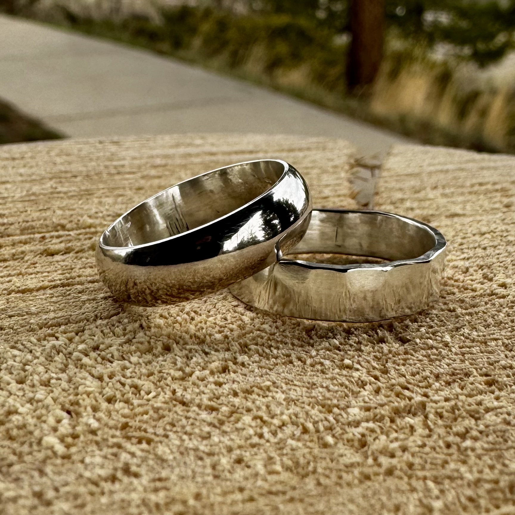 Two silver rings with different finishes are placed on a textured wooden surface in Grand County Colorado.