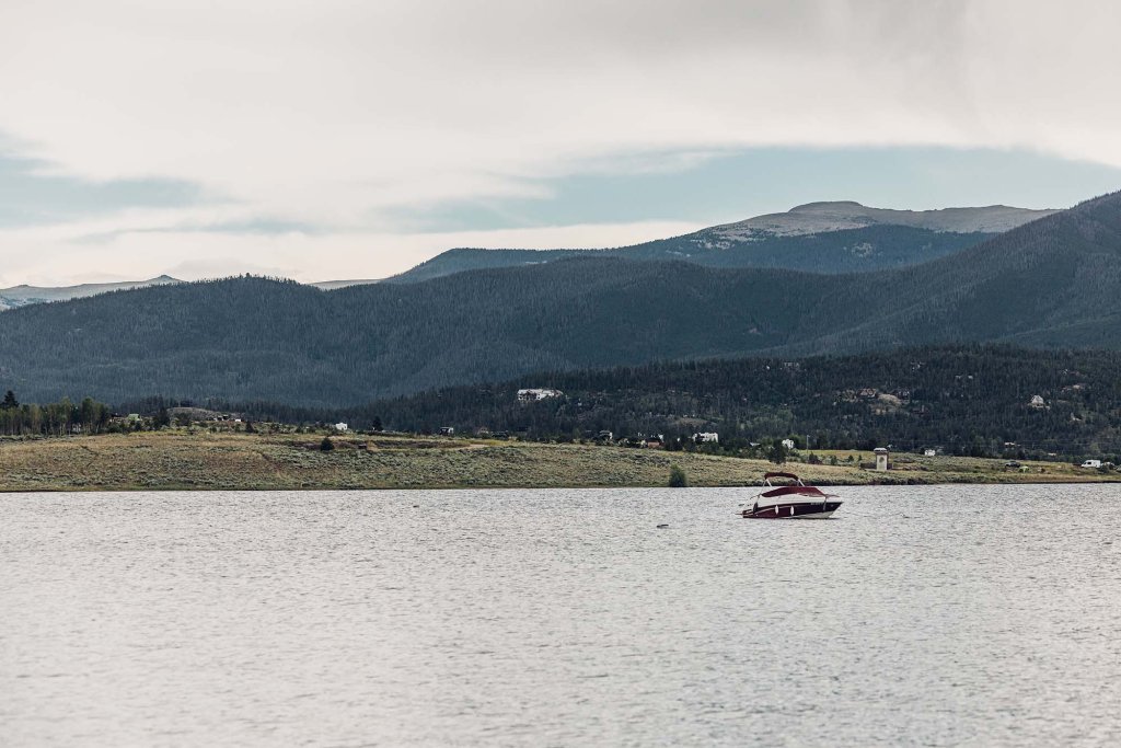 A boat on Lake Granby surrounded by green landscapes and tree-covered mountains.