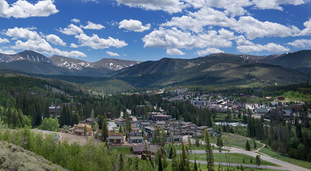 A picturesque mountain town nestled among lush green forests with snow-capped peaks in the distance in Grand County Colorado.