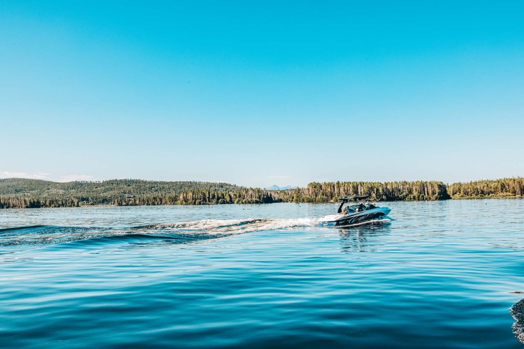 Motorboat cruising across Grand Lake near Trail Ridge Marina, with forested shoreline and mountain views.