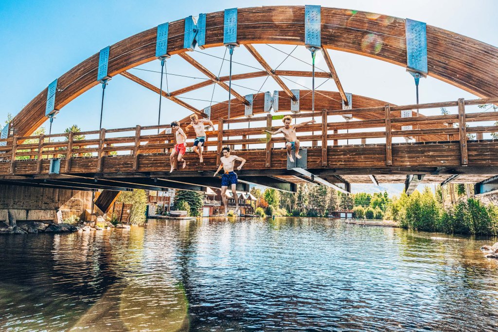 Swimmers jumping from Rainbow Bridge into the water of Grand Lake in Grand Lake, Colorado.