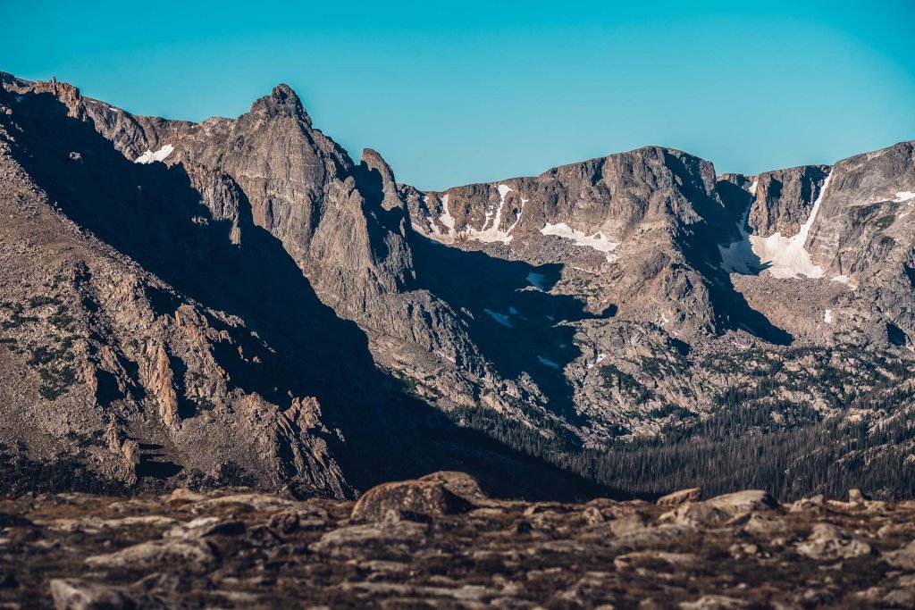 Mountain peaks in Rocky Mountain National Park with patches of snow and alpine terrain.
