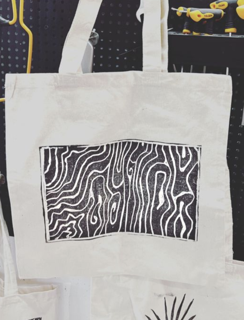 A canvas tote bag featuring a black and white abstract wood grain pattern print in Grand County Colorado.
