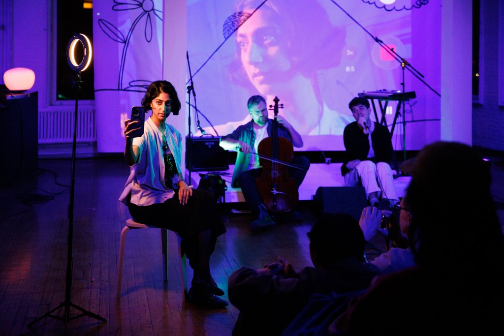 A woman records herself on a phone while musicians perform on a purple-lit stage in Grand County Colorado.