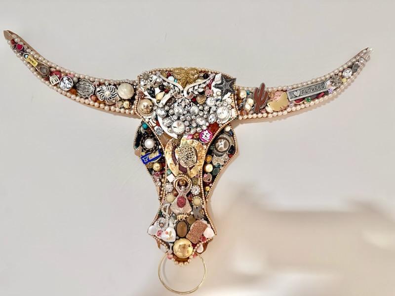 A decorative bull skull wall hanging covered in various vintage jewelry and trinkets in Grand County Colorado.