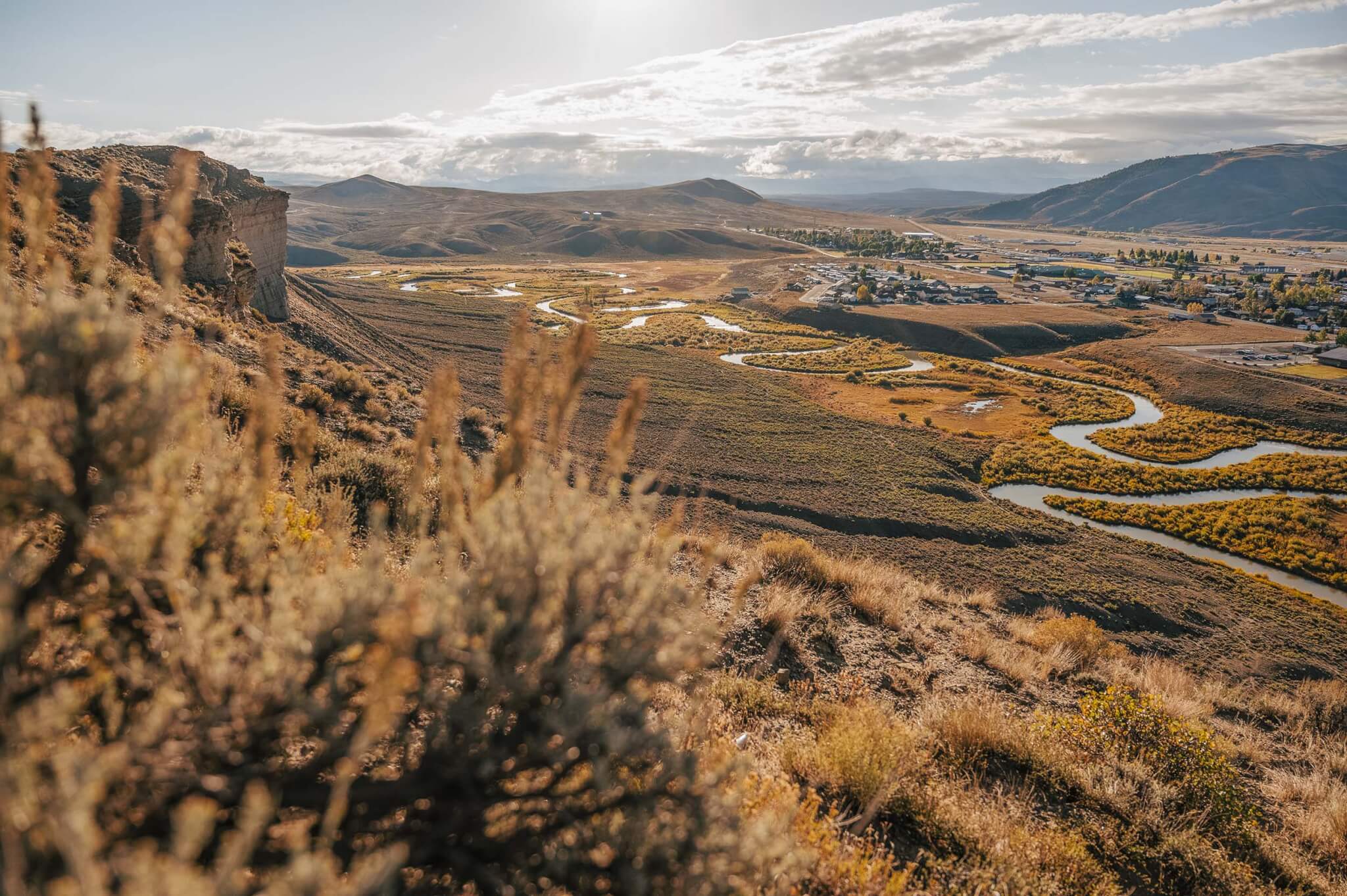 A winding river flows through a dry, grassy valley near a small town in Grand County Colorado.