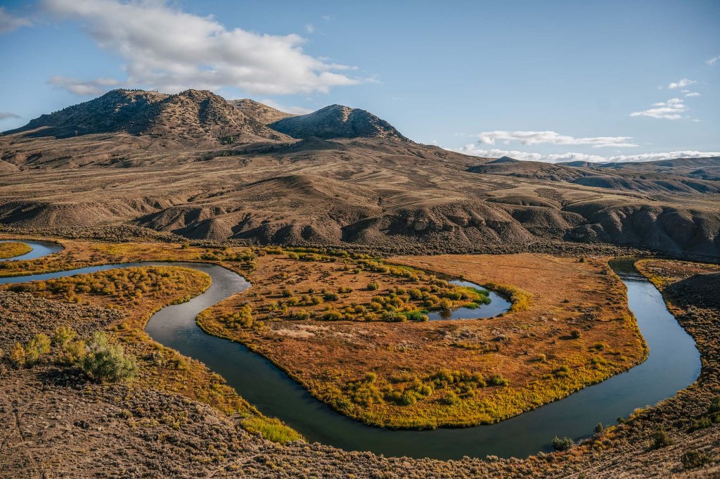 Winding river flowing through a broad valley surrounded by rugged mountain terrain near Kremmling, Colorado.